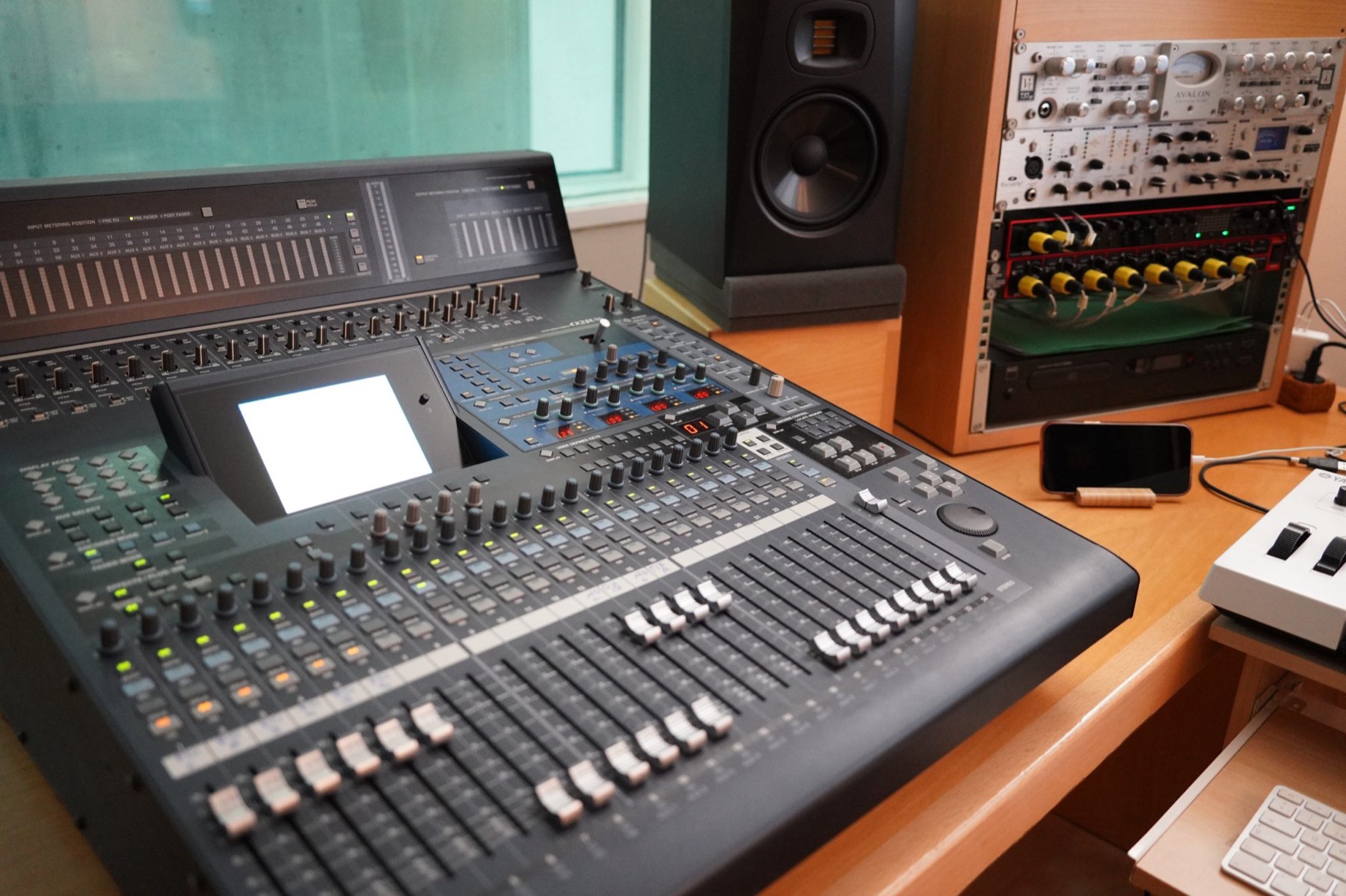 A digital mixing console beside studio monitors